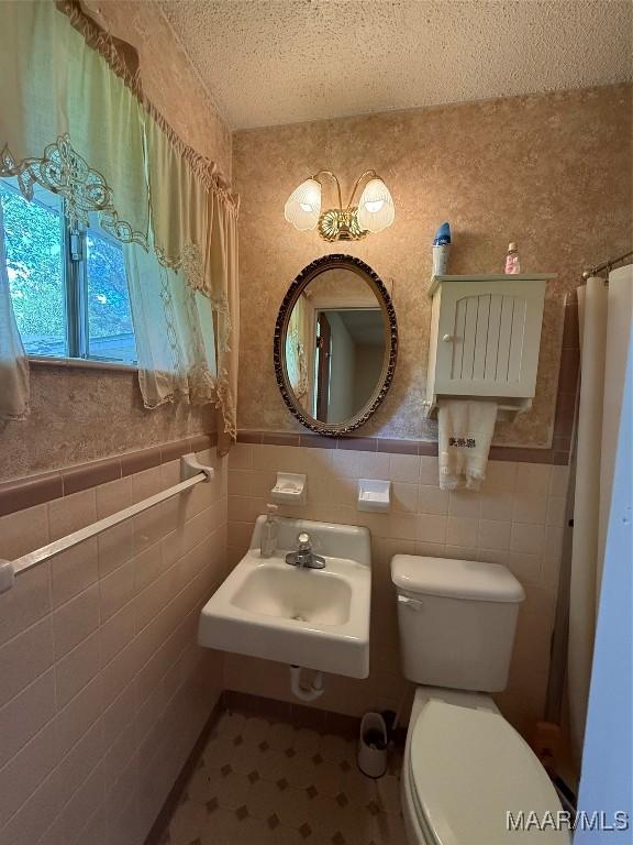 20 Glendale Dr, Selma, AL 36701 - bathroom with a sink, tile walls, toilet, a textured ceiling, and wainscoting