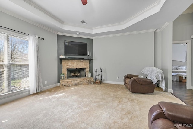 carpeted living area with a tray ceiling, plenty of natural light, a fireplace, and visible vents