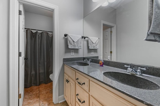 bathroom with tile patterned flooring, a sink, toilet, and double vanity