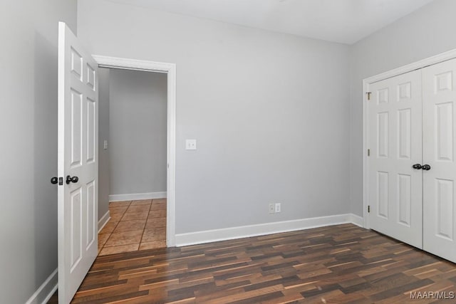 unfurnished bedroom featuring baseboards, dark wood finished floors, and a closet