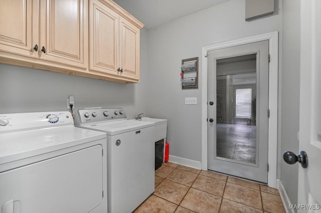 clothes washing area featuring light tile patterned floors, washing machine and clothes dryer, cabinet space, and baseboards