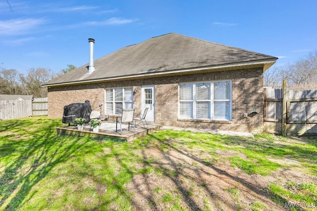 back of property with a yard, brick siding, and fence