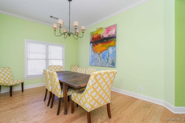 dining room with a notable chandelier, visible vents, light wood-style floors, baseboards, and crown molding