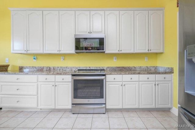 kitchen featuring light tile patterned floors, appliances with stainless steel finishes, white cabinetry, and light stone countertops