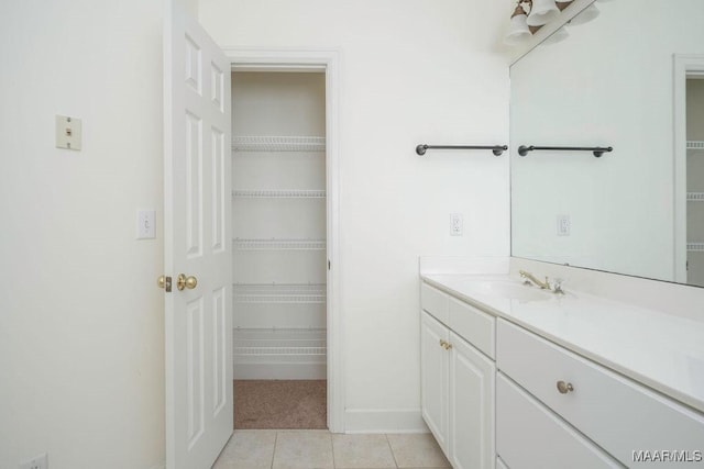 bathroom featuring tile patterned flooring, vanity, baseboards, and a spacious closet