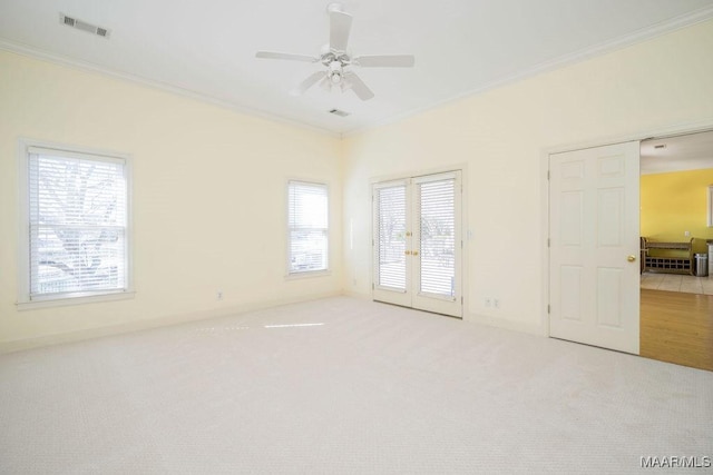 carpeted empty room with french doors, ornamental molding, visible vents, and a ceiling fan