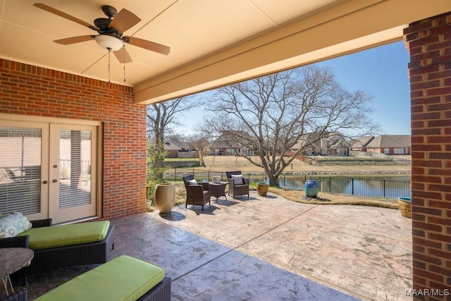 view of patio / terrace featuring a water view, a fenced backyard, a ceiling fan, and french doors