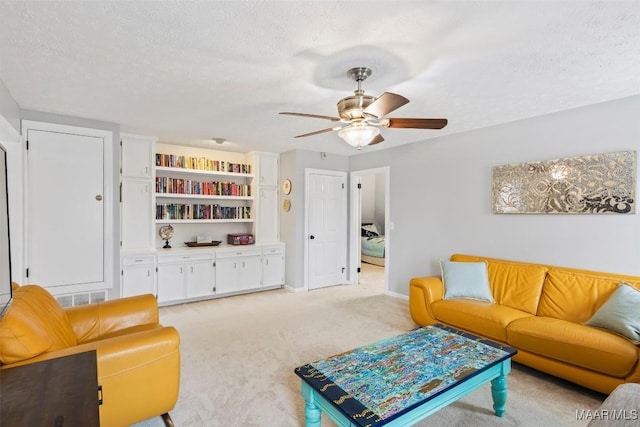 living room with a textured ceiling, ceiling fan, light colored carpet, visible vents, and baseboards