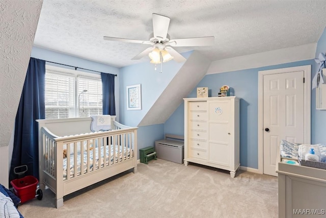 bedroom featuring light colored carpet, ceiling fan, vaulted ceiling, a textured ceiling, and a crib