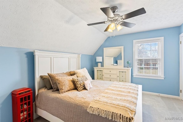 bedroom with carpet, a ceiling fan, vaulted ceiling, a textured ceiling, and baseboards