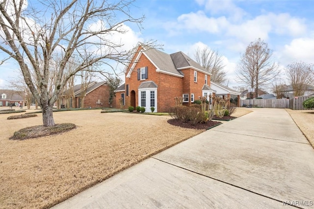 view of side of property with brick siding, a yard, fence, a residential view, and driveway