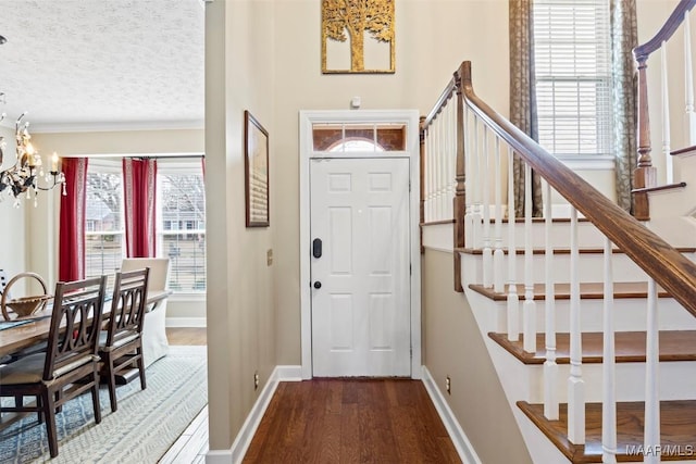 foyer entrance with stairway, a textured ceiling, an inviting chandelier, and wood finished floors