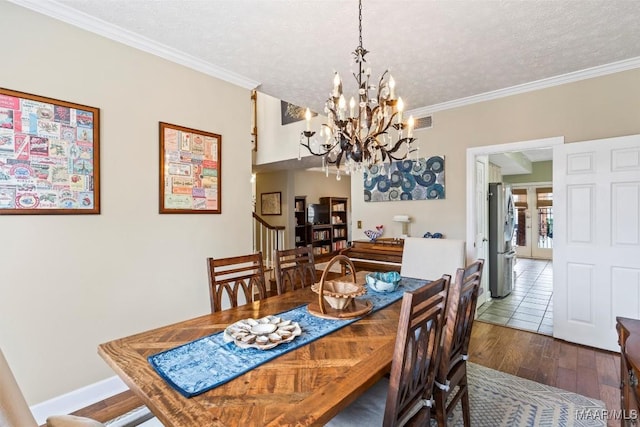 dining area featuring ornamental molding, a textured ceiling, baseboards, and wood finished floors