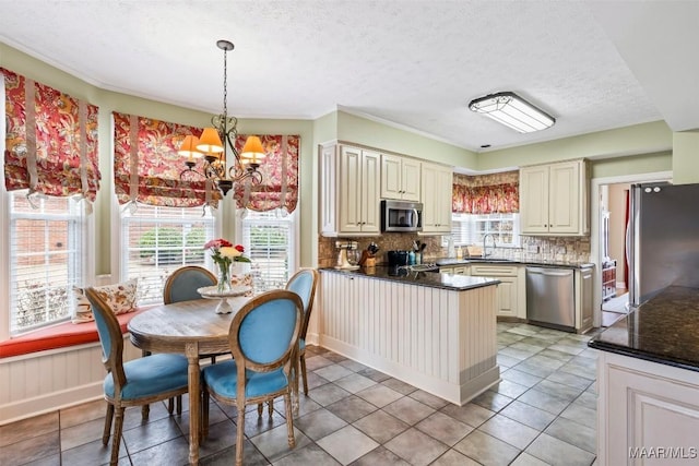 kitchen with stainless steel appliances, dark countertops, a sink, and tasteful backsplash