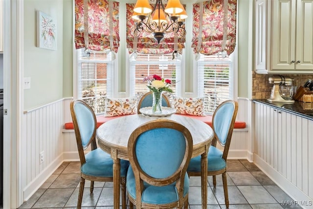 dining room with light tile patterned floors, wainscoting, and a notable chandelier