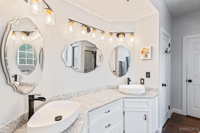 full bath with double vanity, wood finished floors, and a sink