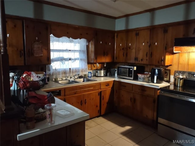 kitchen featuring brown cabinets, light countertops, stainless steel microwave, black range with electric stovetop, and a sink