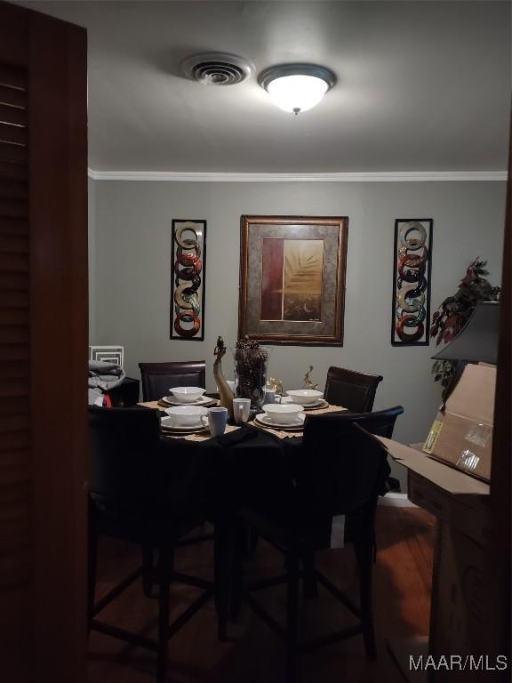 dining area featuring visible vents, crown molding, and wood finished floors