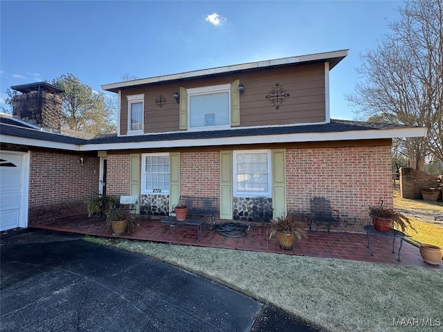 view of front of house with brick siding, a chimney, and an attached garage