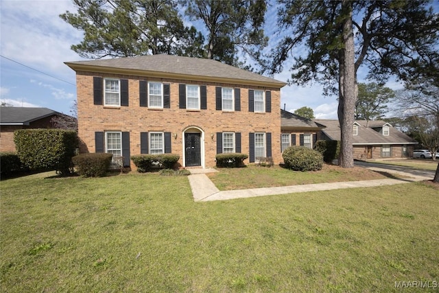 colonial house featuring a front lawn and brick siding