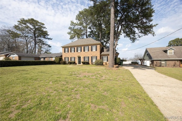 view of front facade with brick siding, concrete driveway, and a front yard