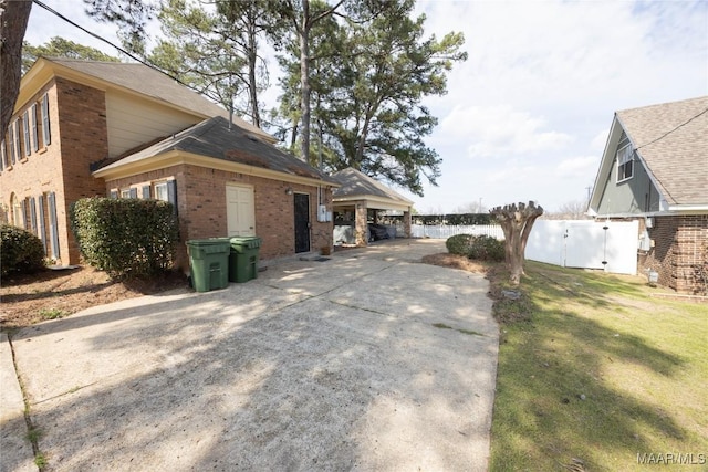 view of home's exterior featuring brick siding, a yard, and fence