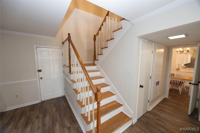 staircase with a chandelier, visible vents, crown molding, and wood finished floors