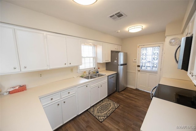 kitchen with stainless steel appliances, a wealth of natural light, visible vents, white cabinets, and a sink