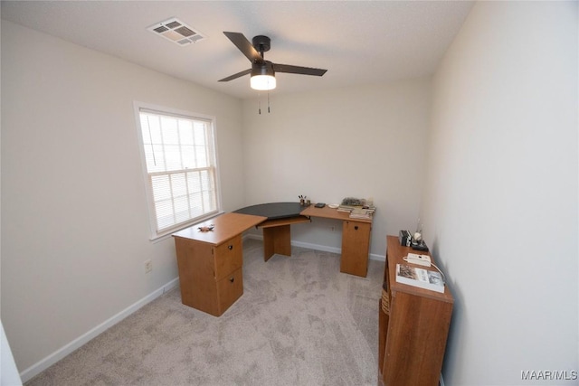 office space featuring baseboards, a ceiling fan, visible vents, and light colored carpet