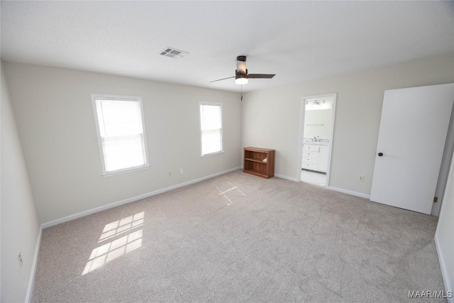 unfurnished bedroom with carpet floors, a ceiling fan, visible vents, baseboards, and ensuite bath