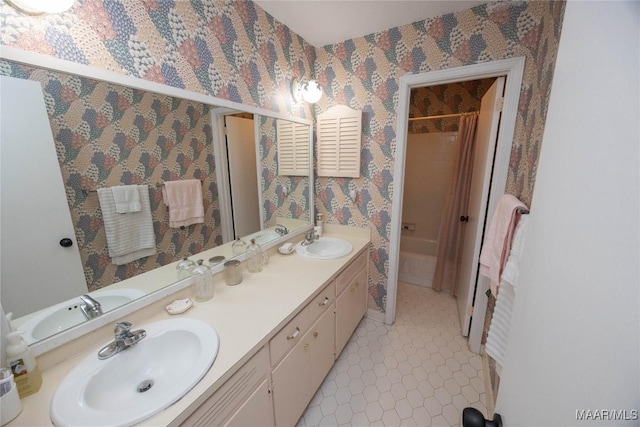 bathroom featuring double vanity, wallpapered walls, and a sink