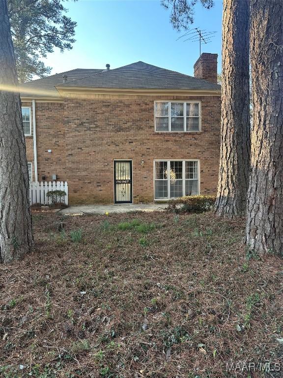 back of house featuring brick siding and a chimney