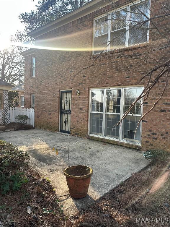 back of house featuring a patio, brick siding, and fence