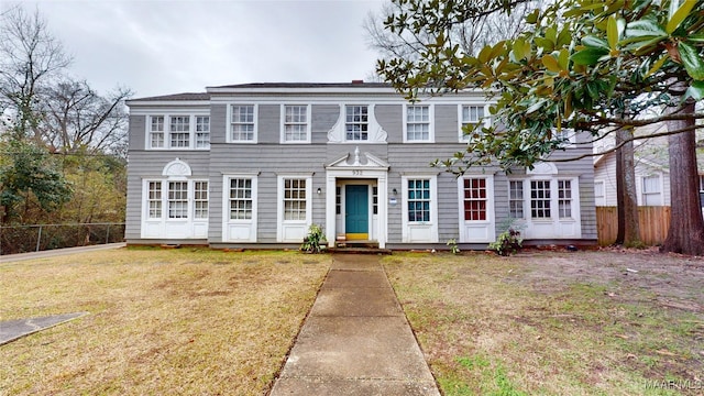 colonial-style house featuring fence and a front yard