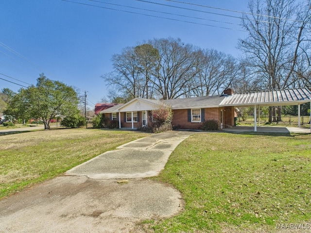 view of front of property featuring brick siding, concrete driveway, a chimney, an attached carport, and a front yard