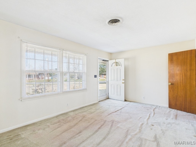 spare room with carpet, visible vents, and baseboards