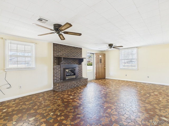 unfurnished living room with baseboards, a fireplace, visible vents, and ceiling fan