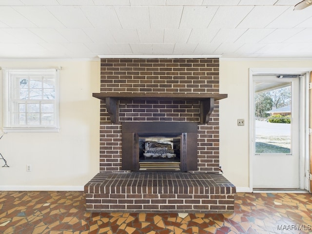 room details featuring a brick fireplace, crown molding, and baseboards