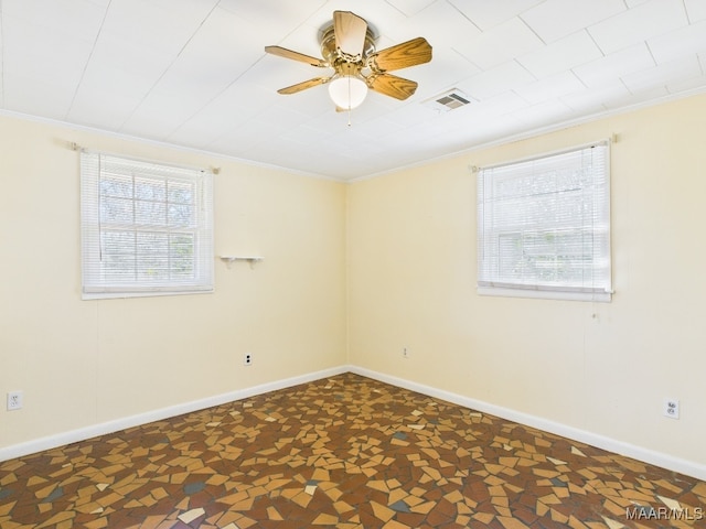 spare room with crown molding, a wealth of natural light, visible vents, and baseboards