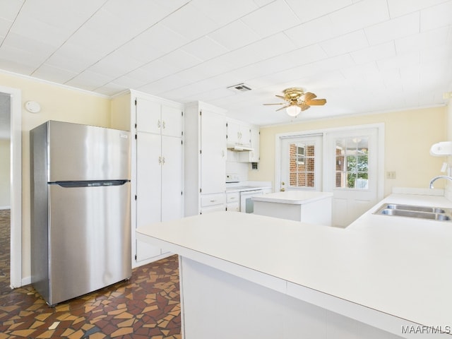 kitchen with ornamental molding, freestanding refrigerator, visible vents, and a sink