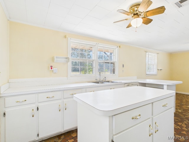 kitchen featuring light countertops, a center island, visible vents, and a sink