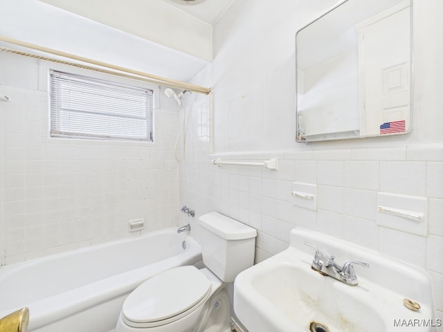 bathroom with toilet, a wainscoted wall, shower / tub combination, a sink, and tile walls