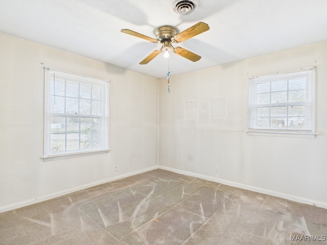 carpeted empty room featuring a healthy amount of sunlight, baseboards, and visible vents