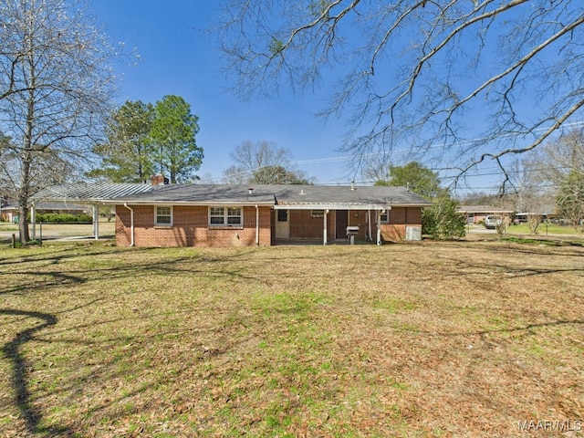 back of house featuring a chimney, a lawn, and brick siding