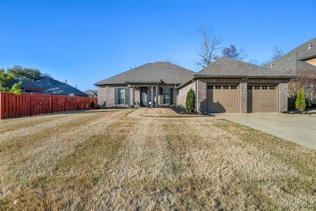 view of front of house with brick siding, concrete driveway, an attached garage, a front yard, and fence