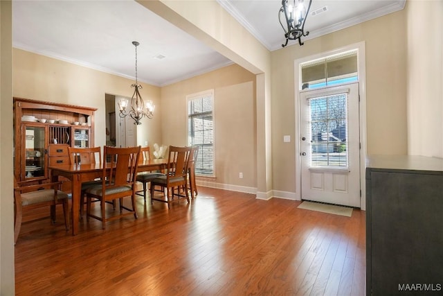 dining space featuring baseboards, visible vents, wood-type flooring, ornamental molding, and a notable chandelier