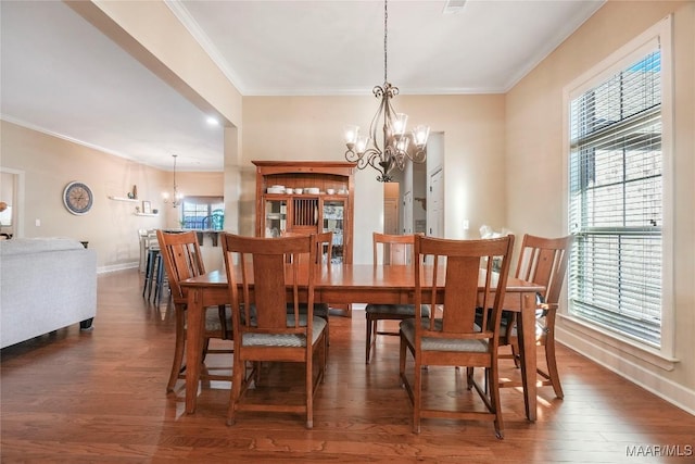 dining area with baseboards, ornamental molding, wood finished floors, and an inviting chandelier