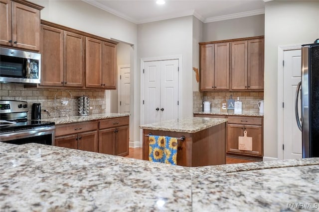 kitchen featuring light stone countertops, appliances with stainless steel finishes, decorative backsplash, brown cabinets, and crown molding