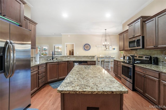 kitchen featuring stainless steel appliances, tasteful backsplash, light wood-style flooring, ornamental molding, and a sink