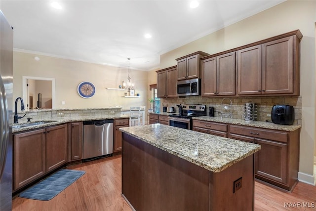 kitchen with crown molding, stainless steel appliances, tasteful backsplash, light wood-style flooring, and a sink